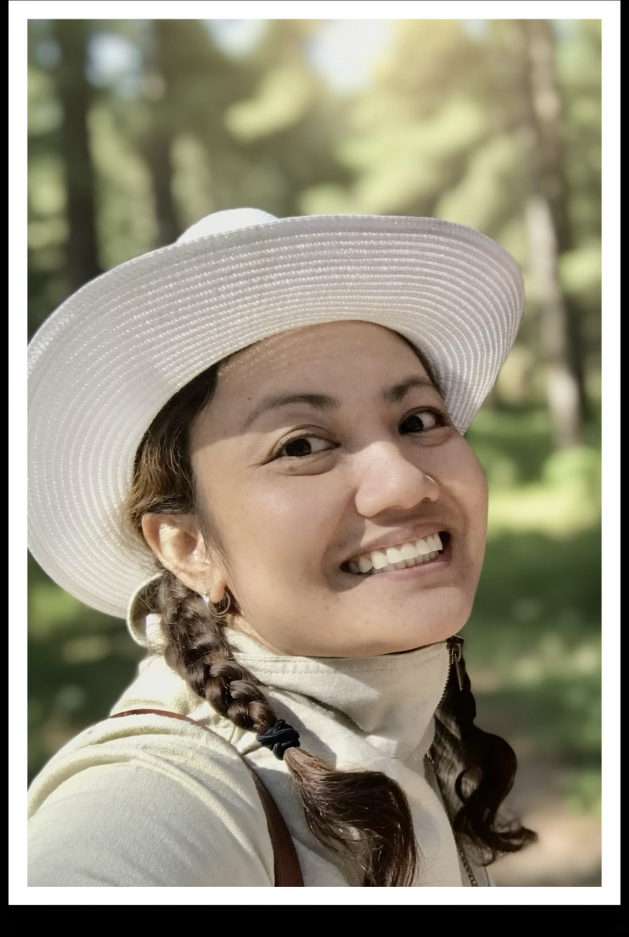 Emily Wallace in a white sun hat, smiling in the woods